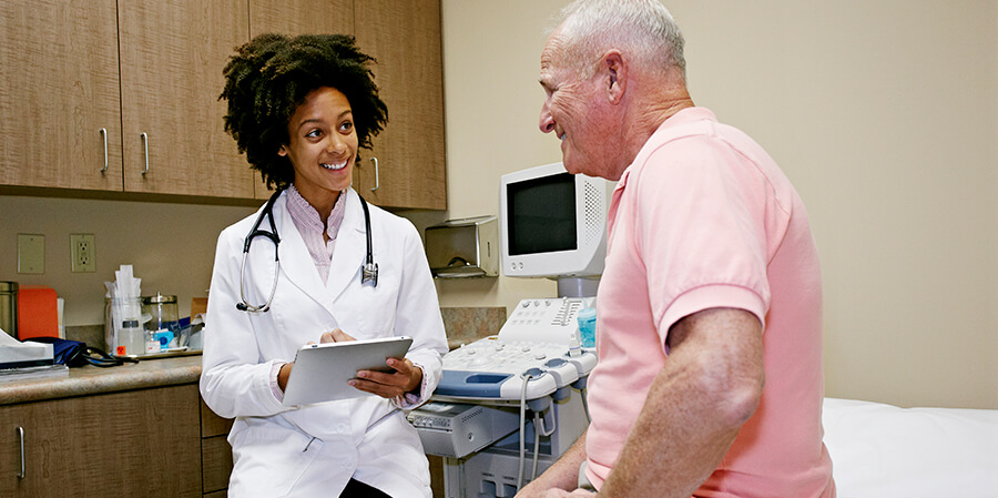 A clinician speaks with a patient in an exam room